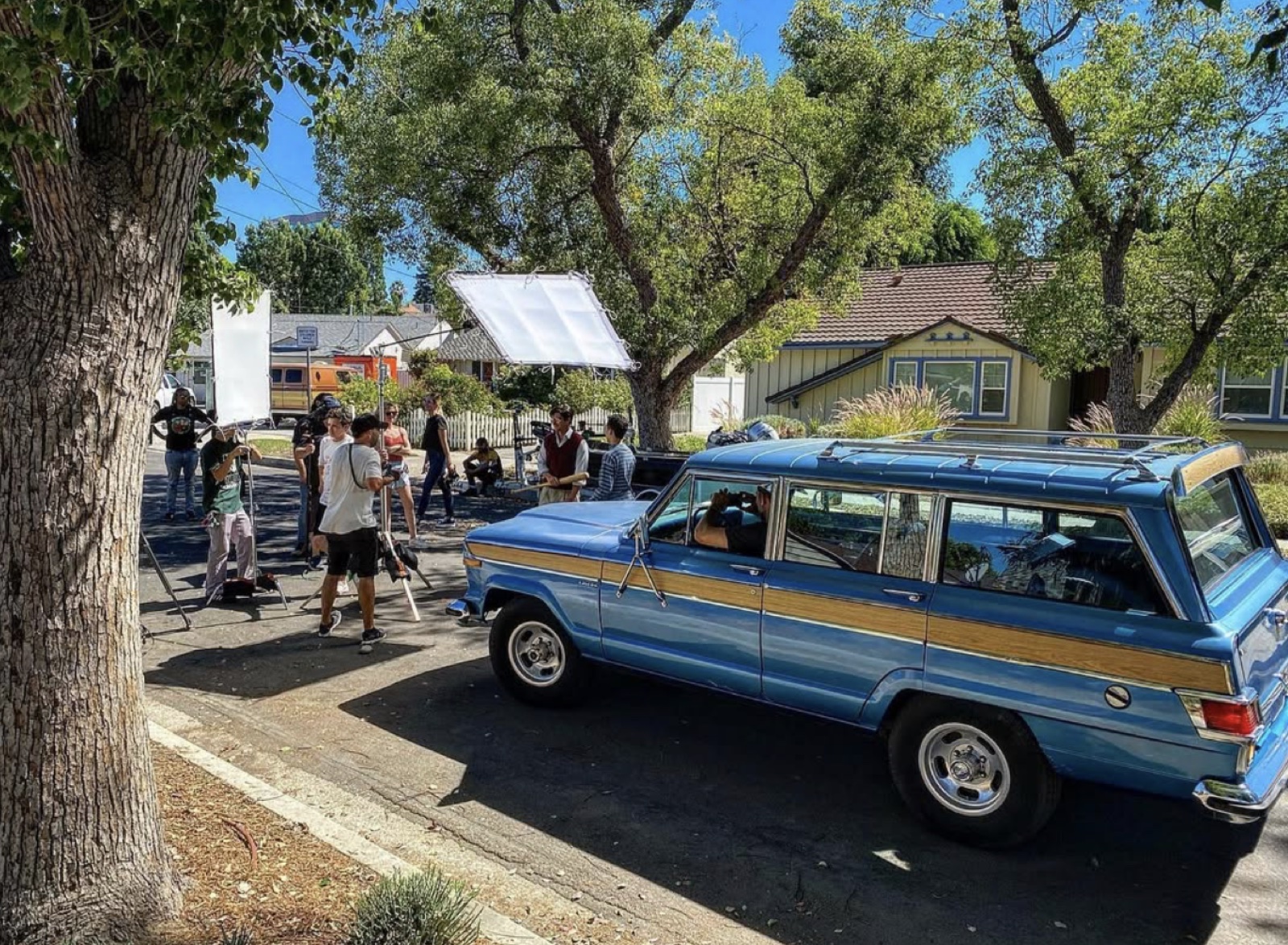Silver Sail crew on a daytime street shoot — bounce board, grip gear, and a vintage Jeep Wagoneer hero car